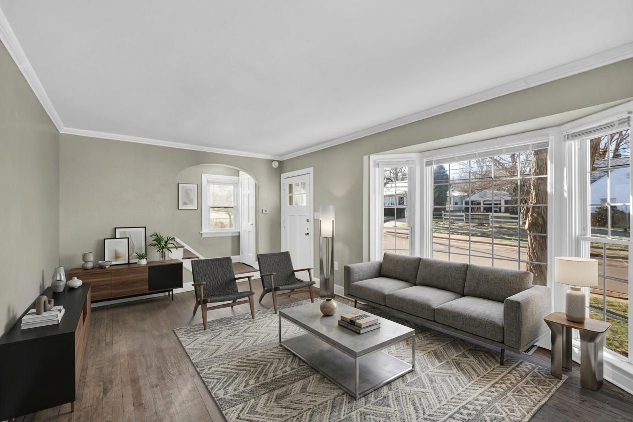 The same living room virtually staged with a grey sofa, two armchairs and a coffee table