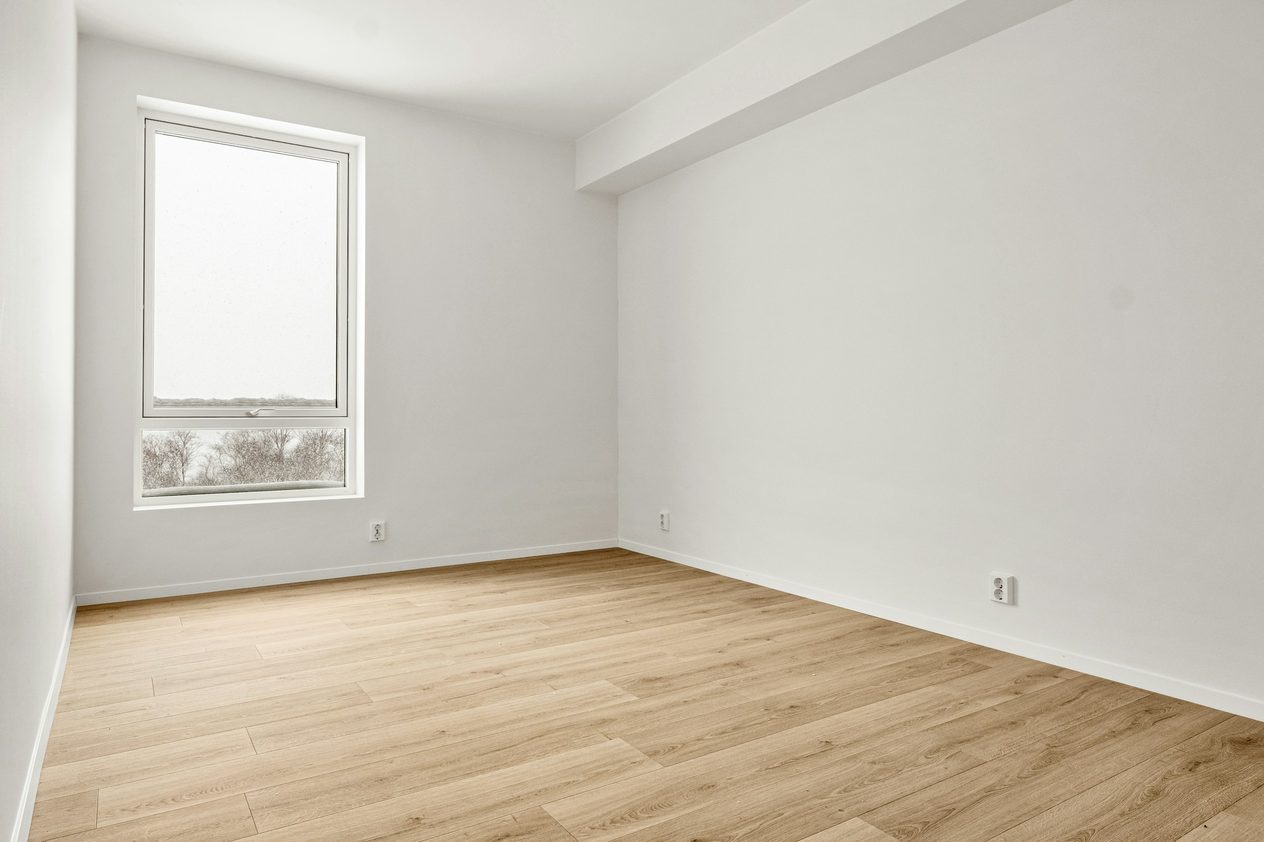 Empty small bedroom with a tall window, before staging
